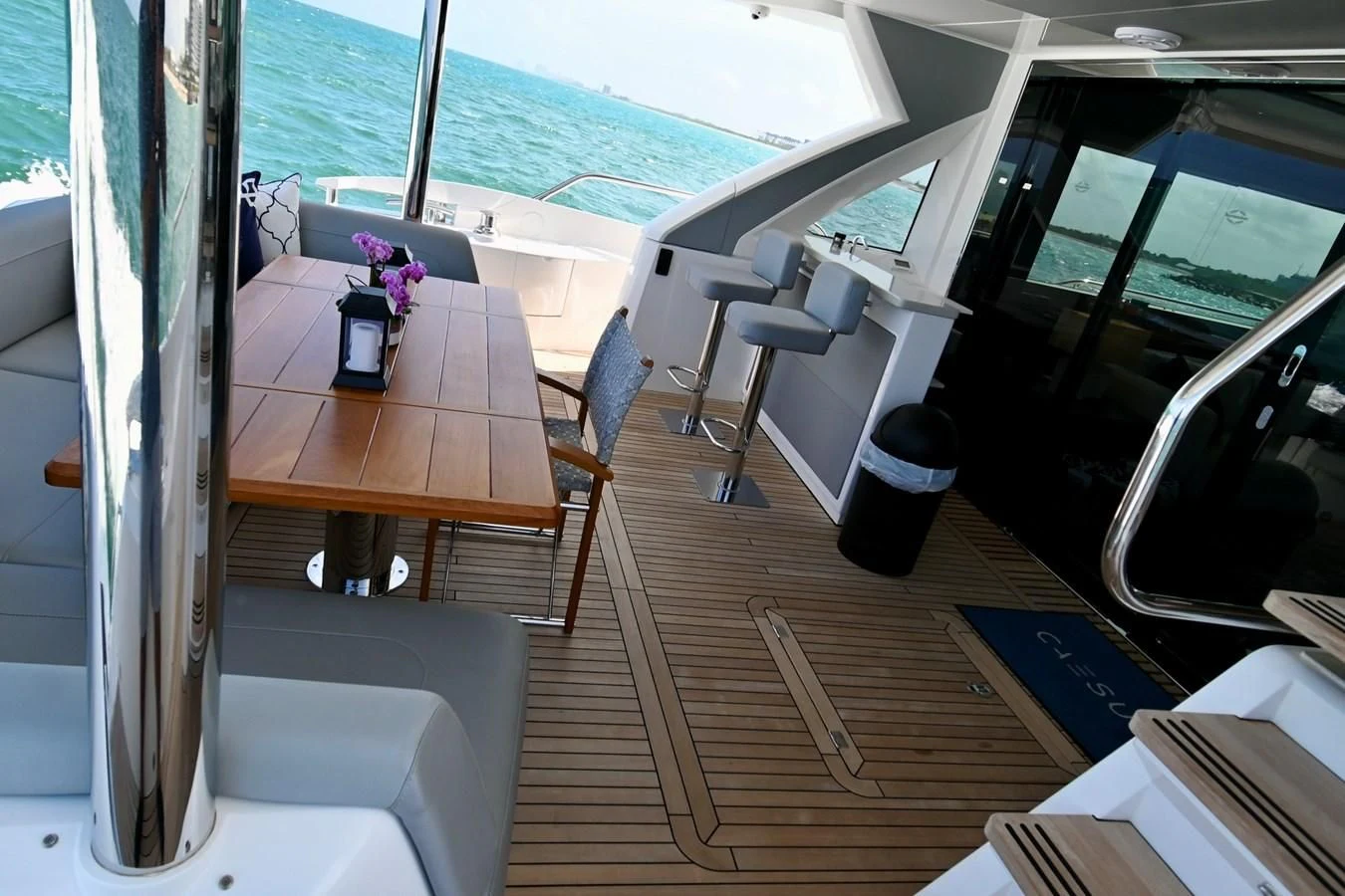 a table with chairs on it next to a window with a body of water in the background aboard CAESURA Yacht for Sale