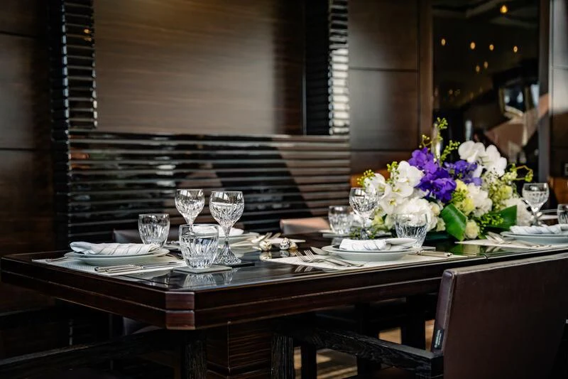 a table with wine glasses and flowers aboard GENESIS Yacht for Sale