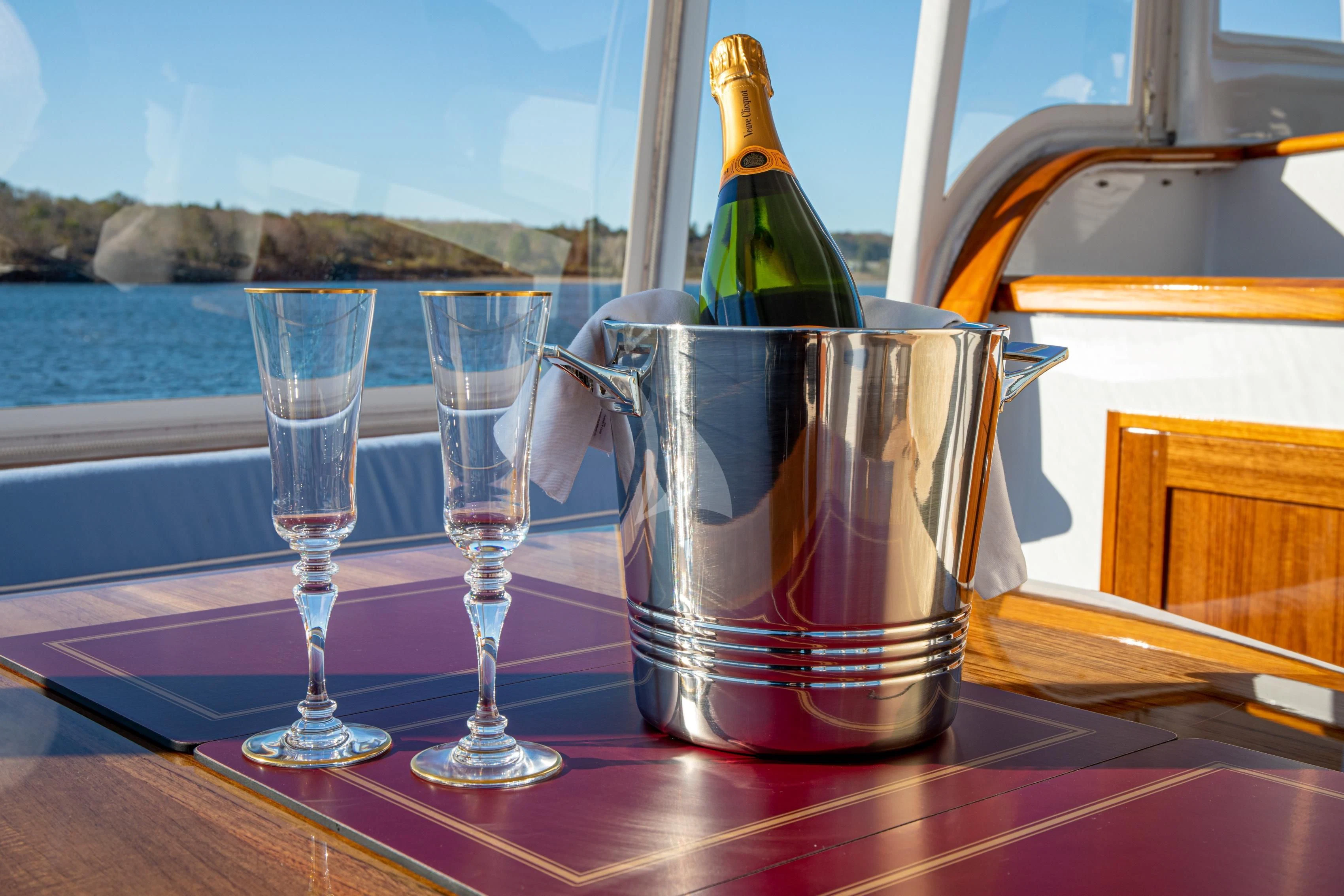 a bottle of champagne and glasses on a table aboard MARYBELLE Yacht for Sale