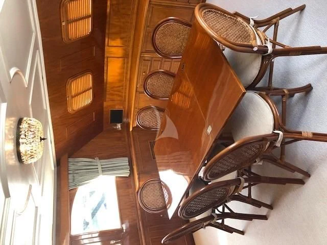 a wooden chair with a round table and chairs in a room with wood floors and windows aboard MARYBELLE Yacht for Sale