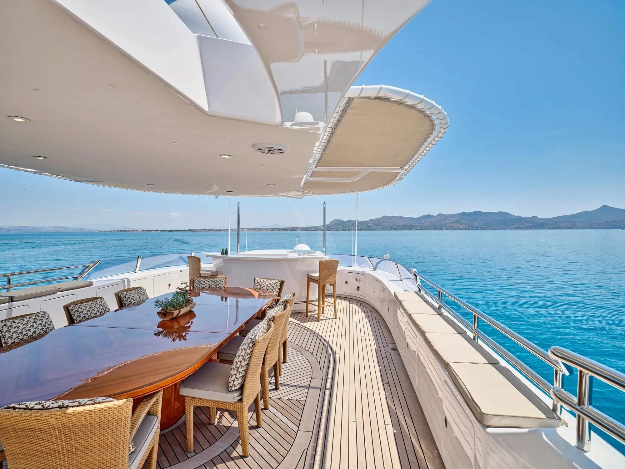 a deck with a table and chairs on it by the water aboard OASIS Yacht for Sale