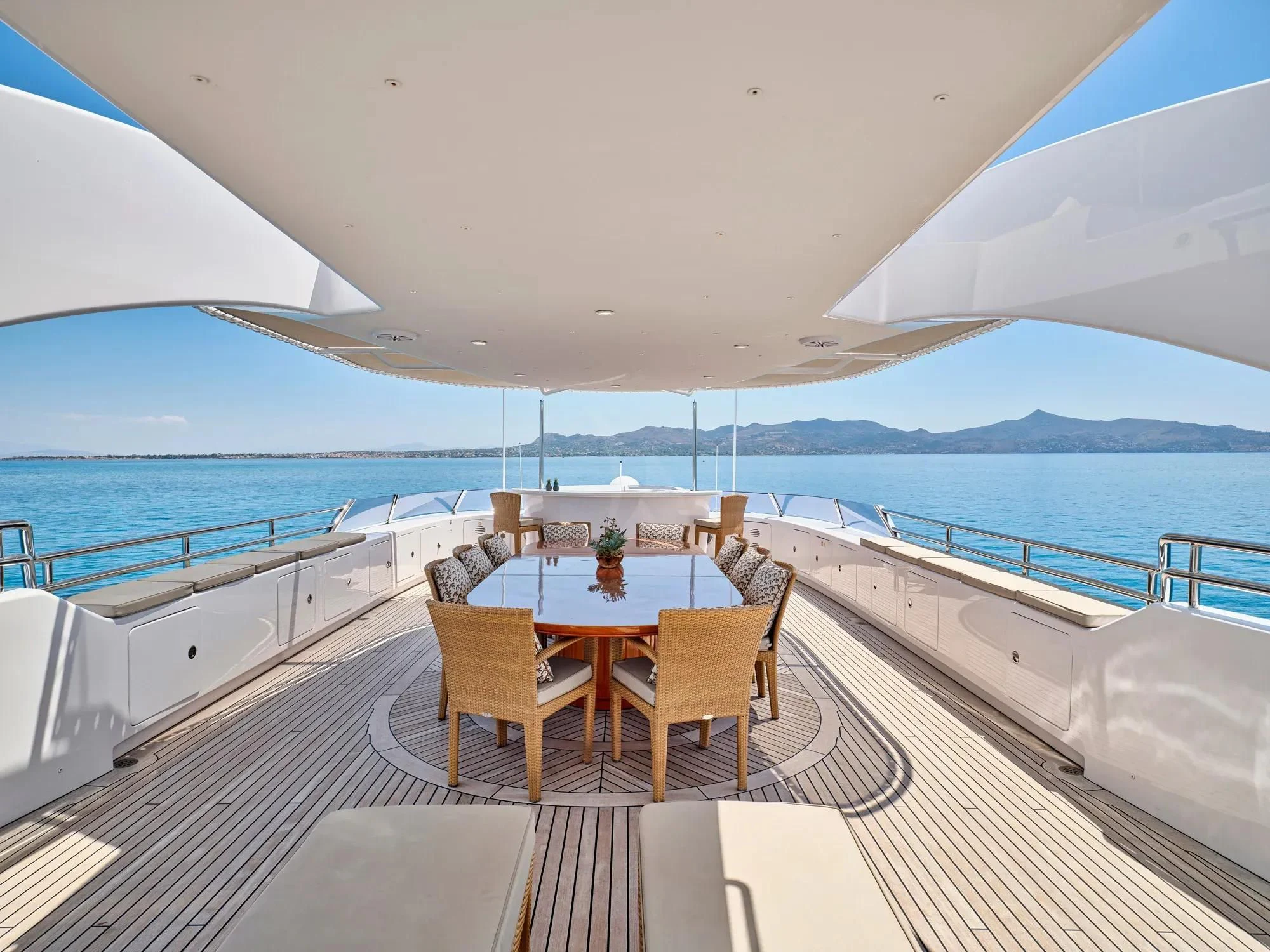 a table and chairs on a deck overlooking a large body of water aboard OASIS Yacht for Sale