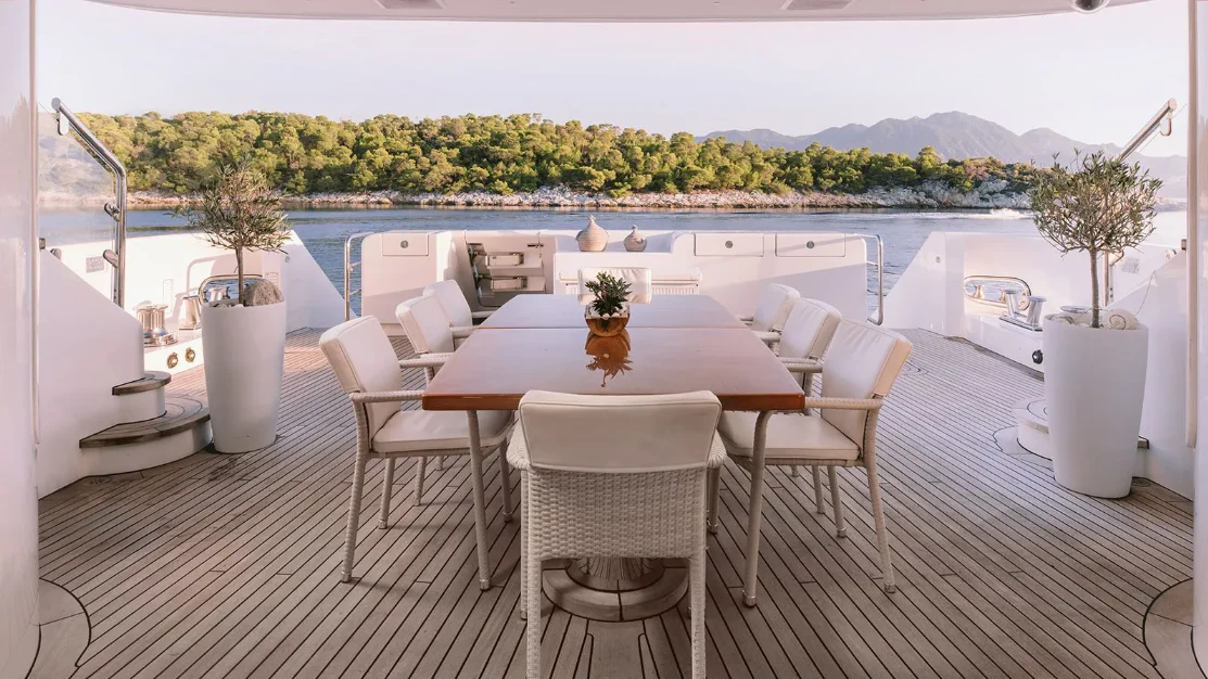 a table and chairs on a deck aboard OASIS Yacht for Sale