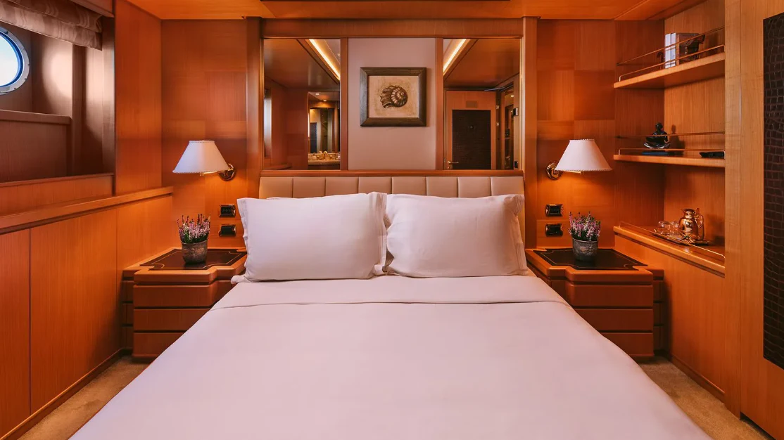 a bed with white sheets and pillows aboard OASIS Yacht for Sale