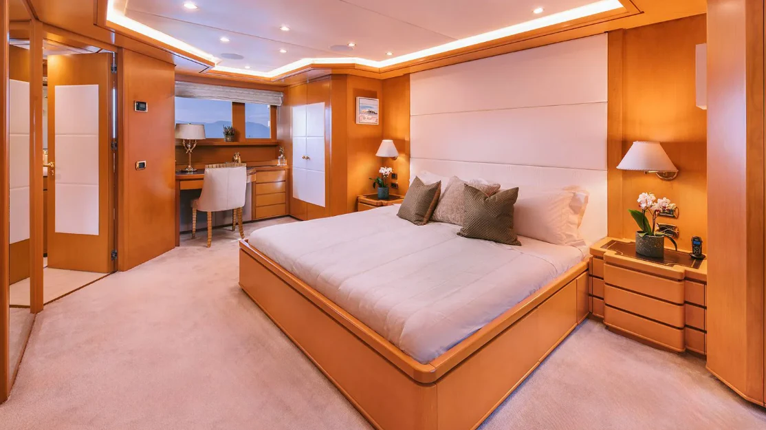 a bedroom with a bed and a desk aboard OASIS Yacht for Sale