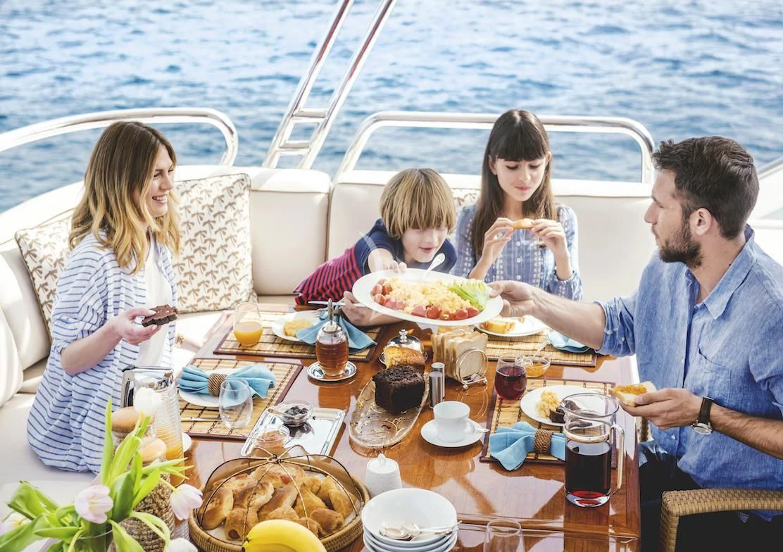 family having dinner at a table aboard OASIS Yacht for Sale