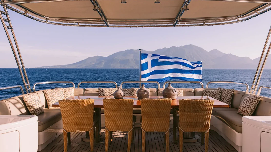 a table with chairs and a flag on it aboard OASIS Yacht for Sale