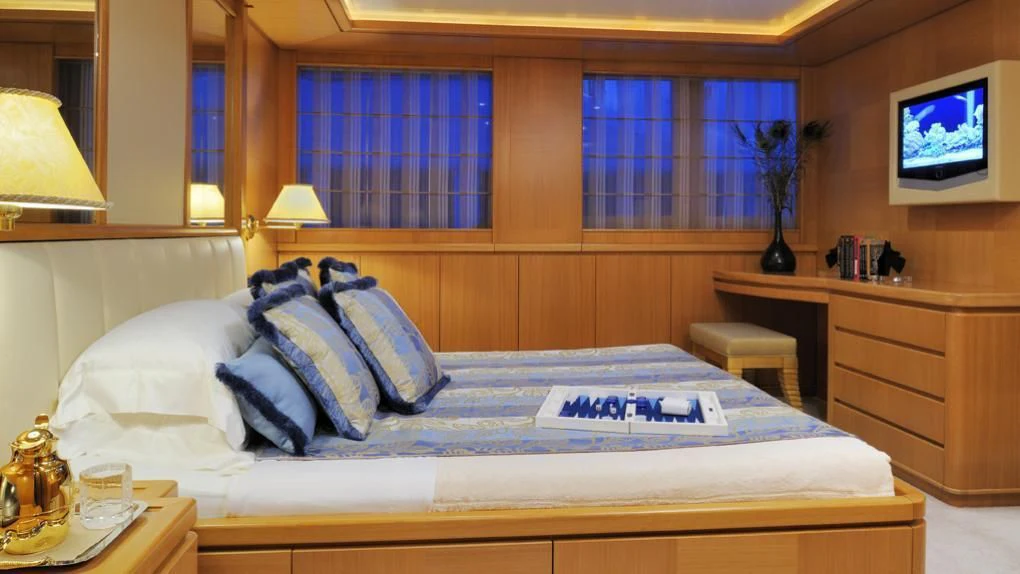 a bed with a white sheet and pillows on it aboard OASIS Yacht for Sale