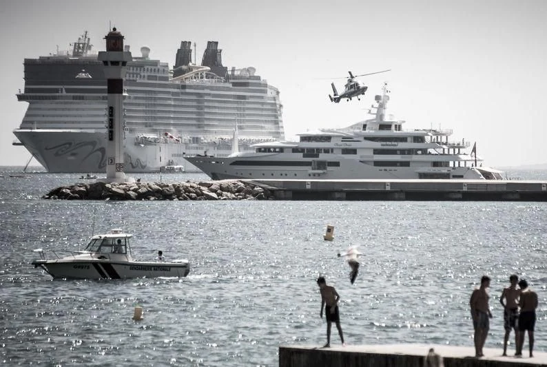 a group of people on a beach with a large ship in the background aboard CHOPI CHOPI Yacht for Sale