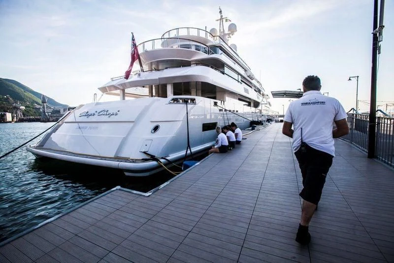 a man walking on a dock next to a large white boat aboard CHOPI CHOPI Yacht for Sale