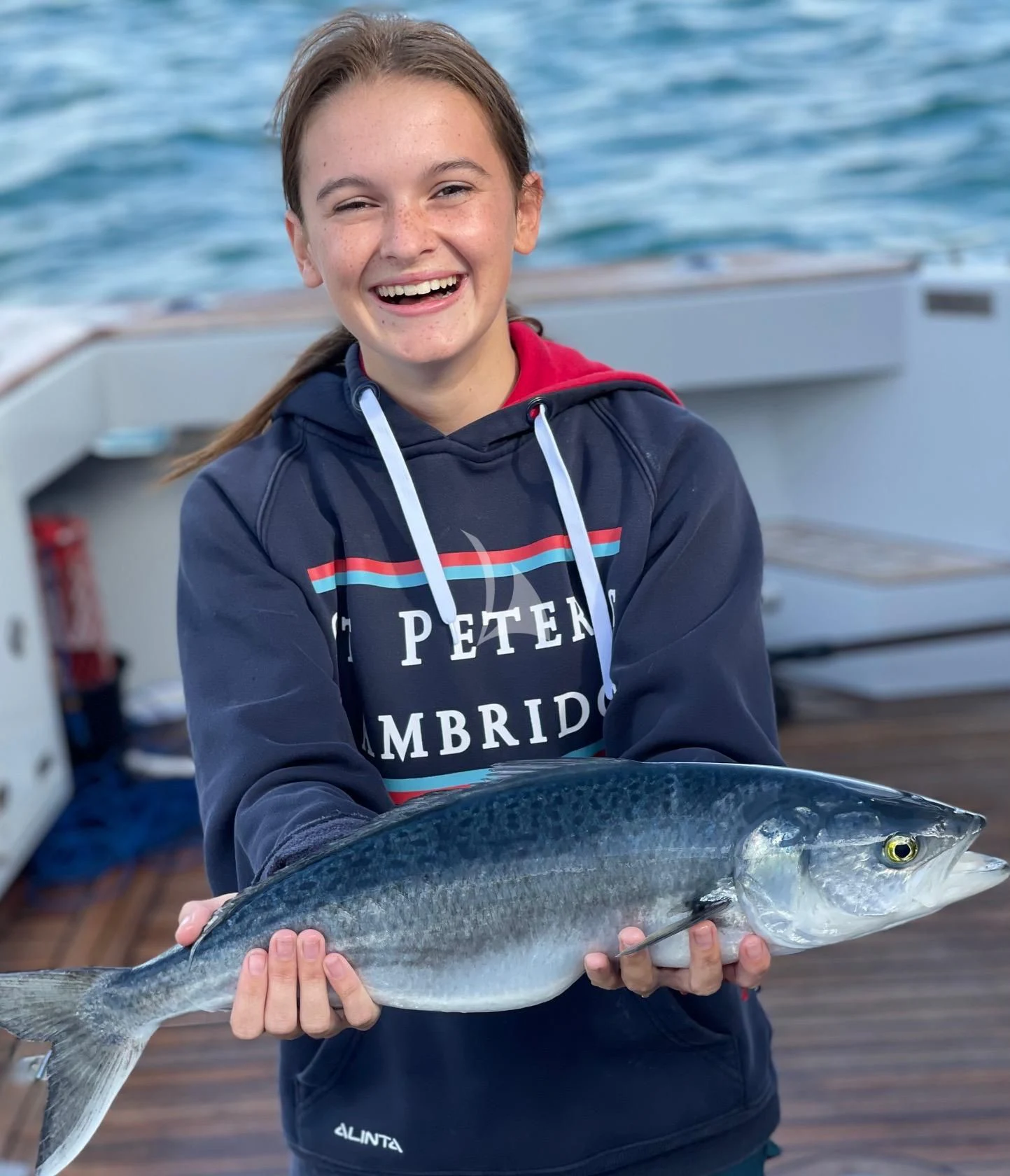a smiling woman holding a fish aboard THE BEAST Yacht for Sale