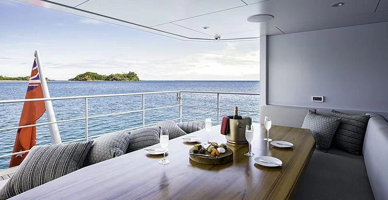 a table with a tray of food and a large body of water aboard THE BEAST Yacht for Sale