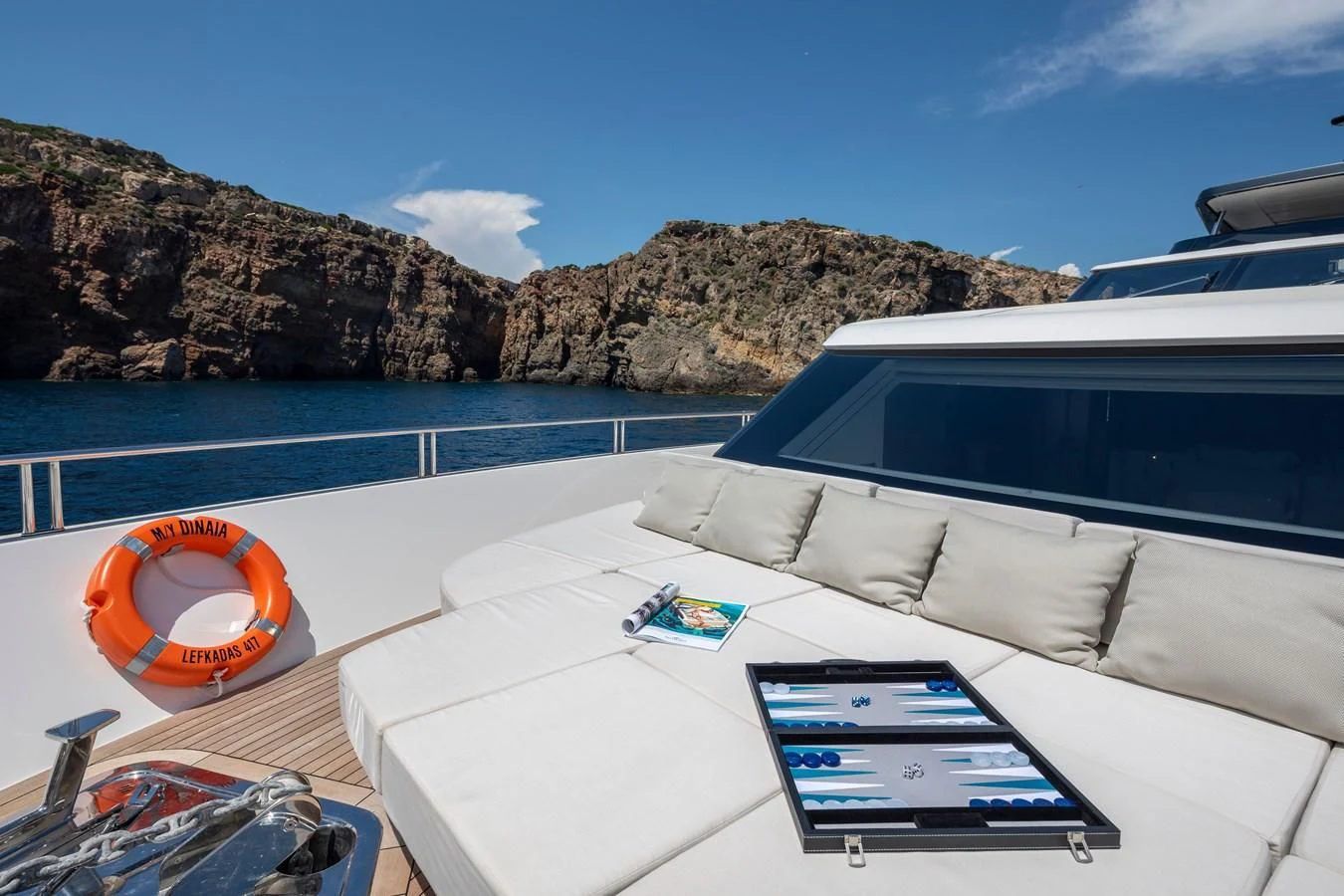a white couch and a pool of water with a large rock and blue sky and a blue sky aboard DINAIA Yacht for Charter