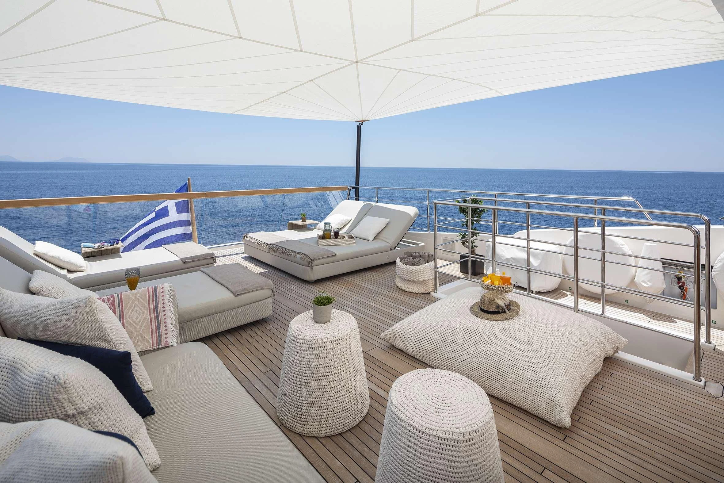 a lounge area with a large white lounge chair and a large body of water aboard DINAIA Yacht for Charter