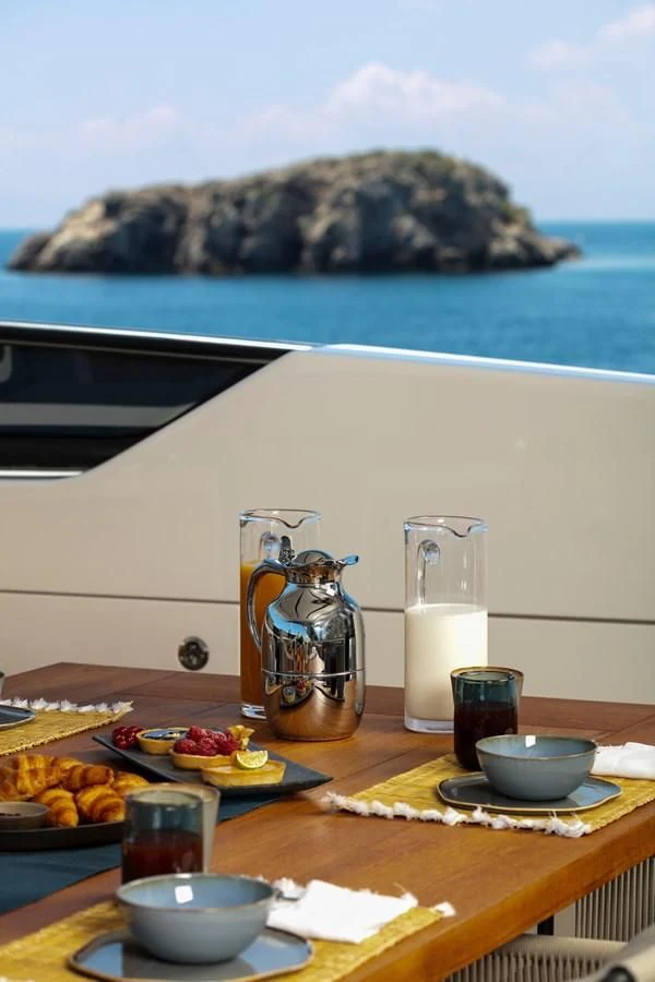 a table with food and drinks on it by a body of water aboard DINAIA Yacht for Charter
