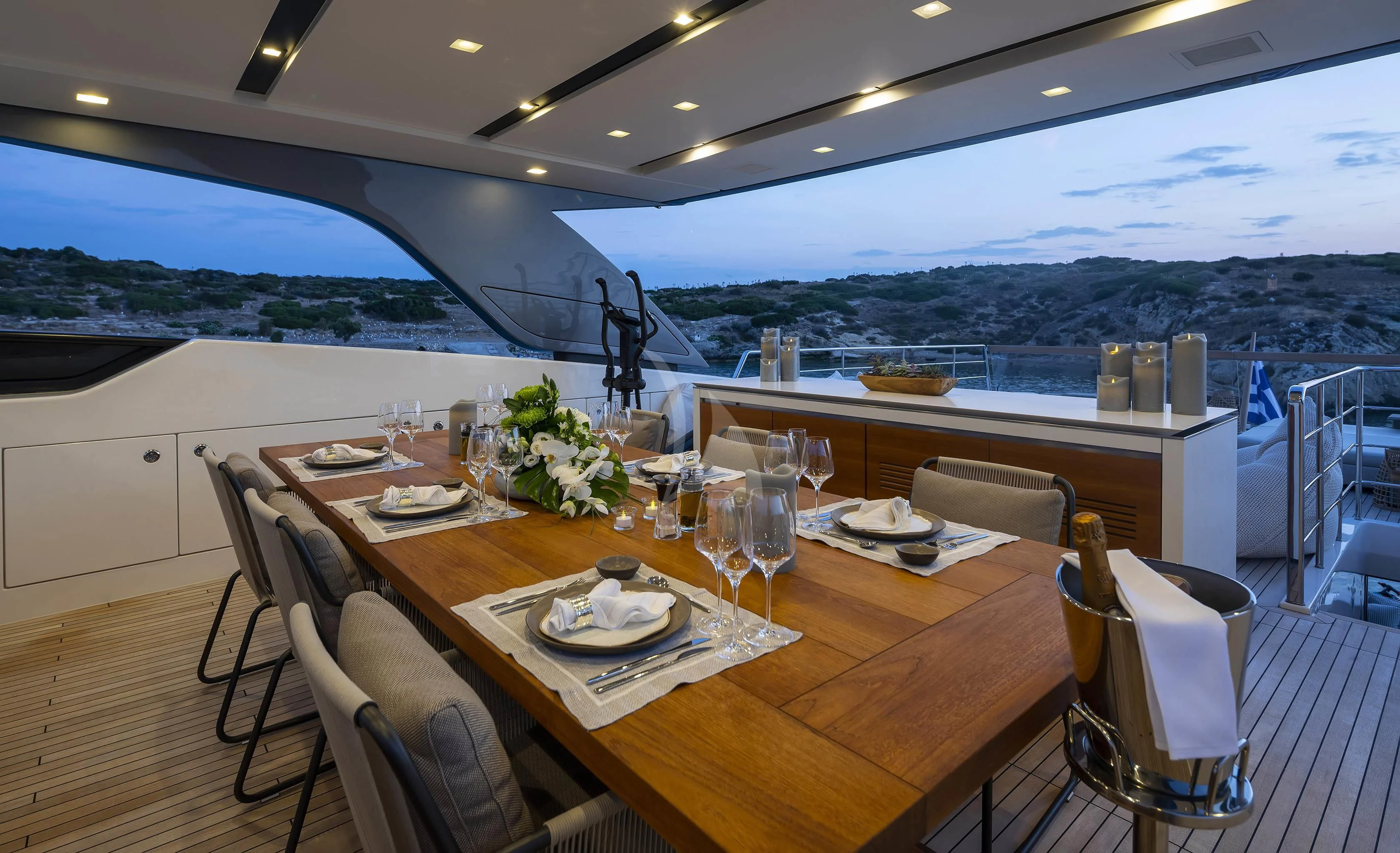 a large dining table with a view of the ocean and mountains aboard DINAIA Yacht for Charter