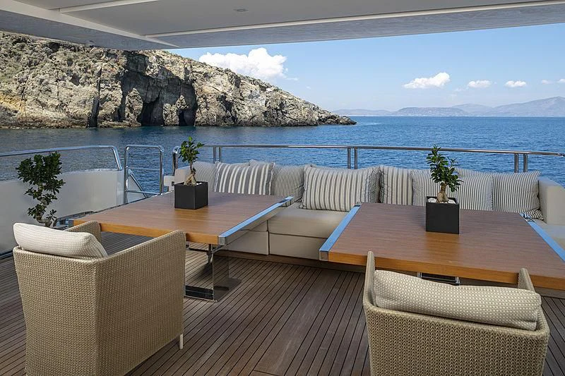 a table and chairs on a deck overlooking a body of water aboard DINAIA Yacht for Charter