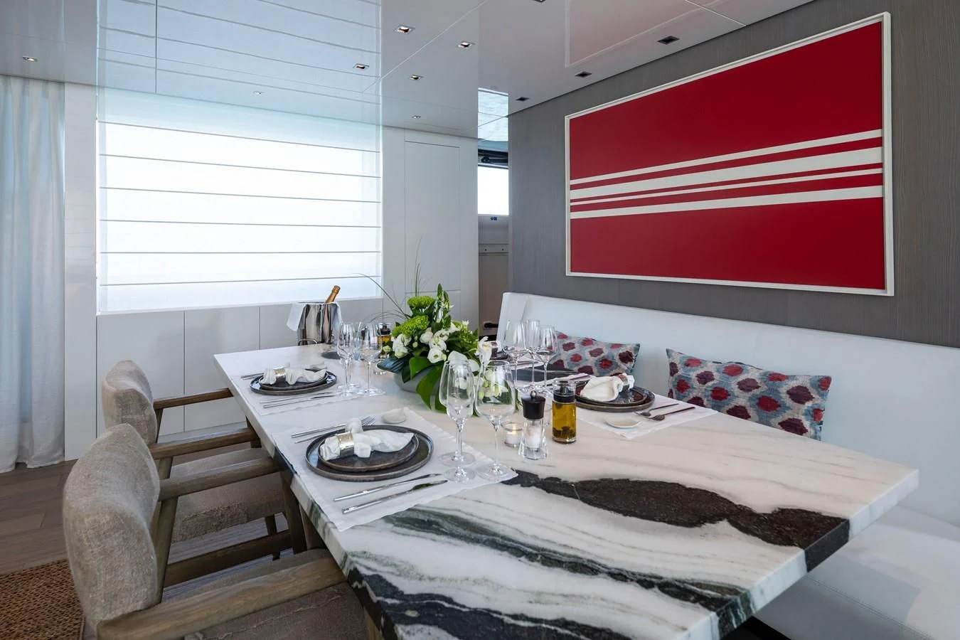 a dining table with a red and white striped pillow and a white tablecloth with a white cloth aboard DINAIA Yacht for Charter