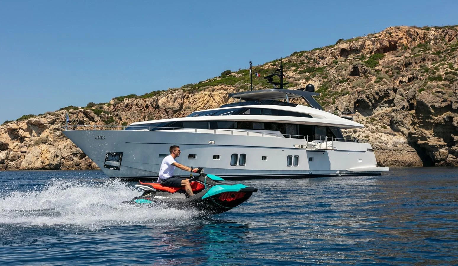 a man on a jet ski in front of a boat aboard DINAIA Yacht for Charter