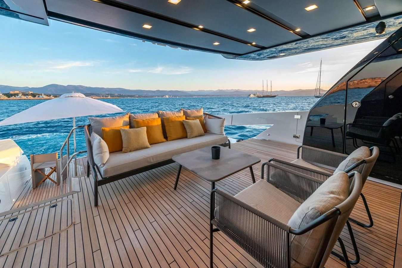 a deck with a couch and a table and chairs on it aboard LOLA Yacht for Sale