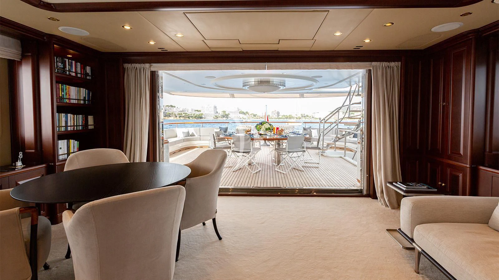 a room with a large window and a table with chairs and a view of the water aboard INCAL Yacht for Sale