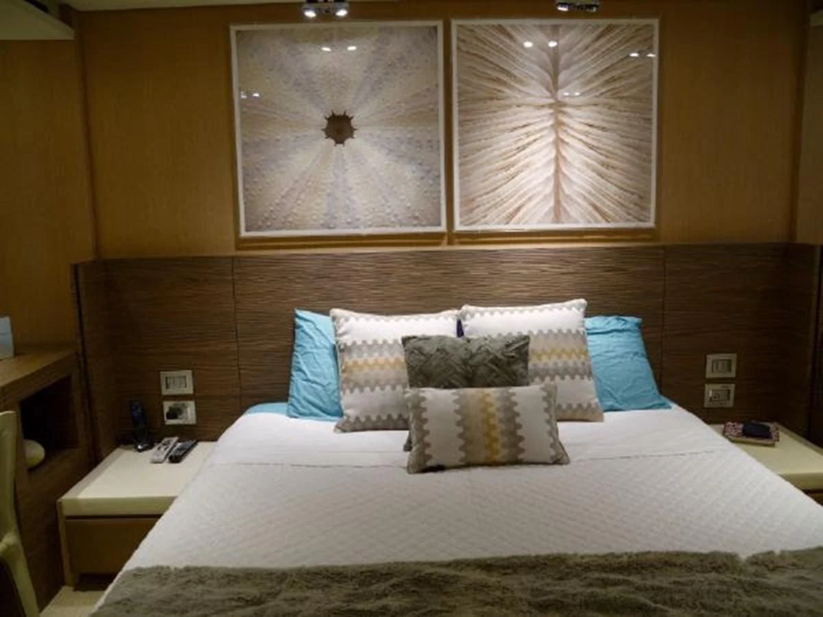 a bed with pillows and a painting above it aboard ASTONISH Yacht for Sale