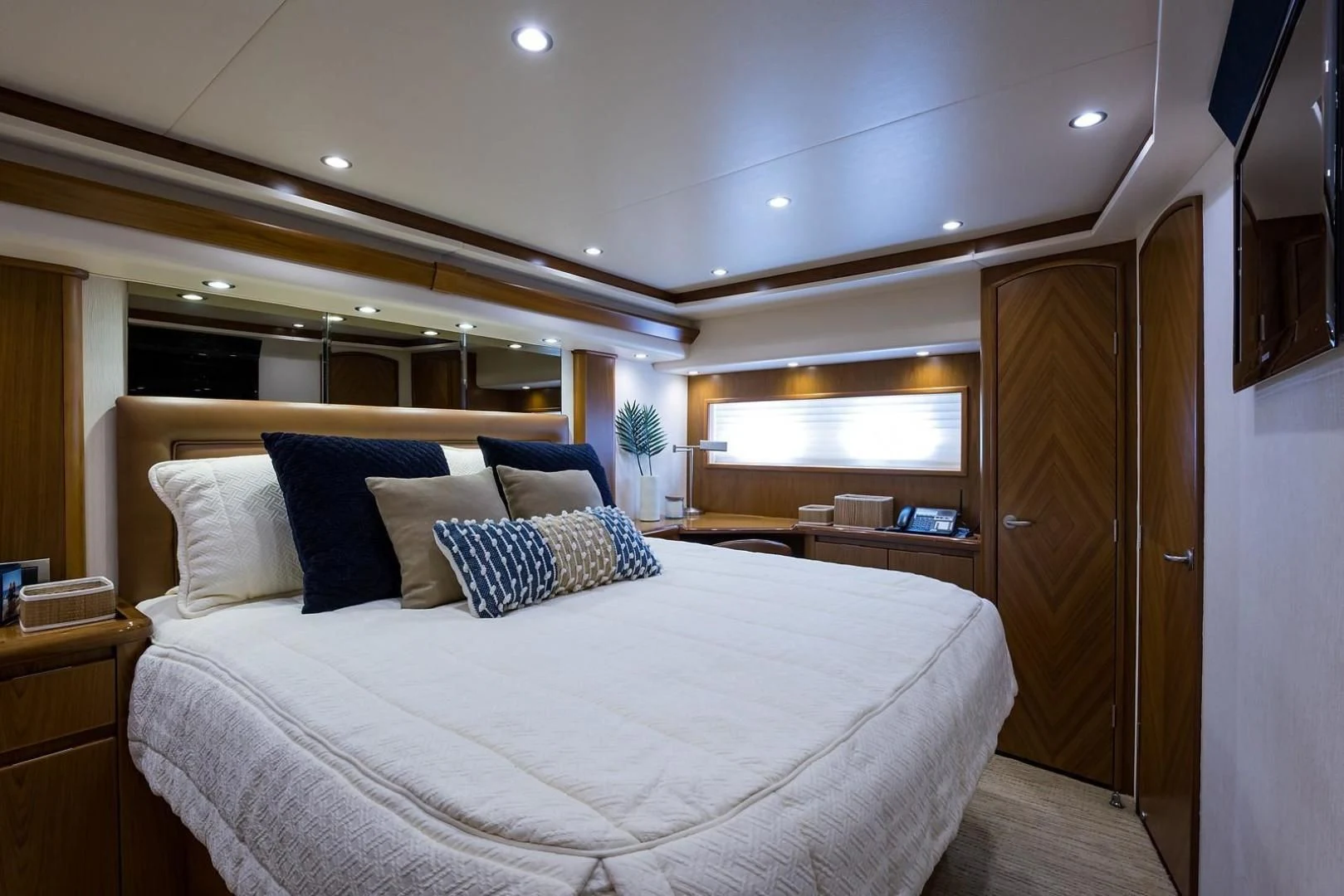 a bed with a white sheet and pillows in a room with wood cabinets aboard LAST CALL Yacht for Sale