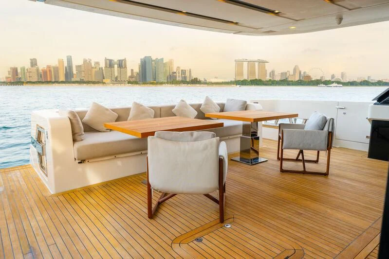 a room with a couch and a table and a large city in the background aboard DA MOON Yacht for Sale