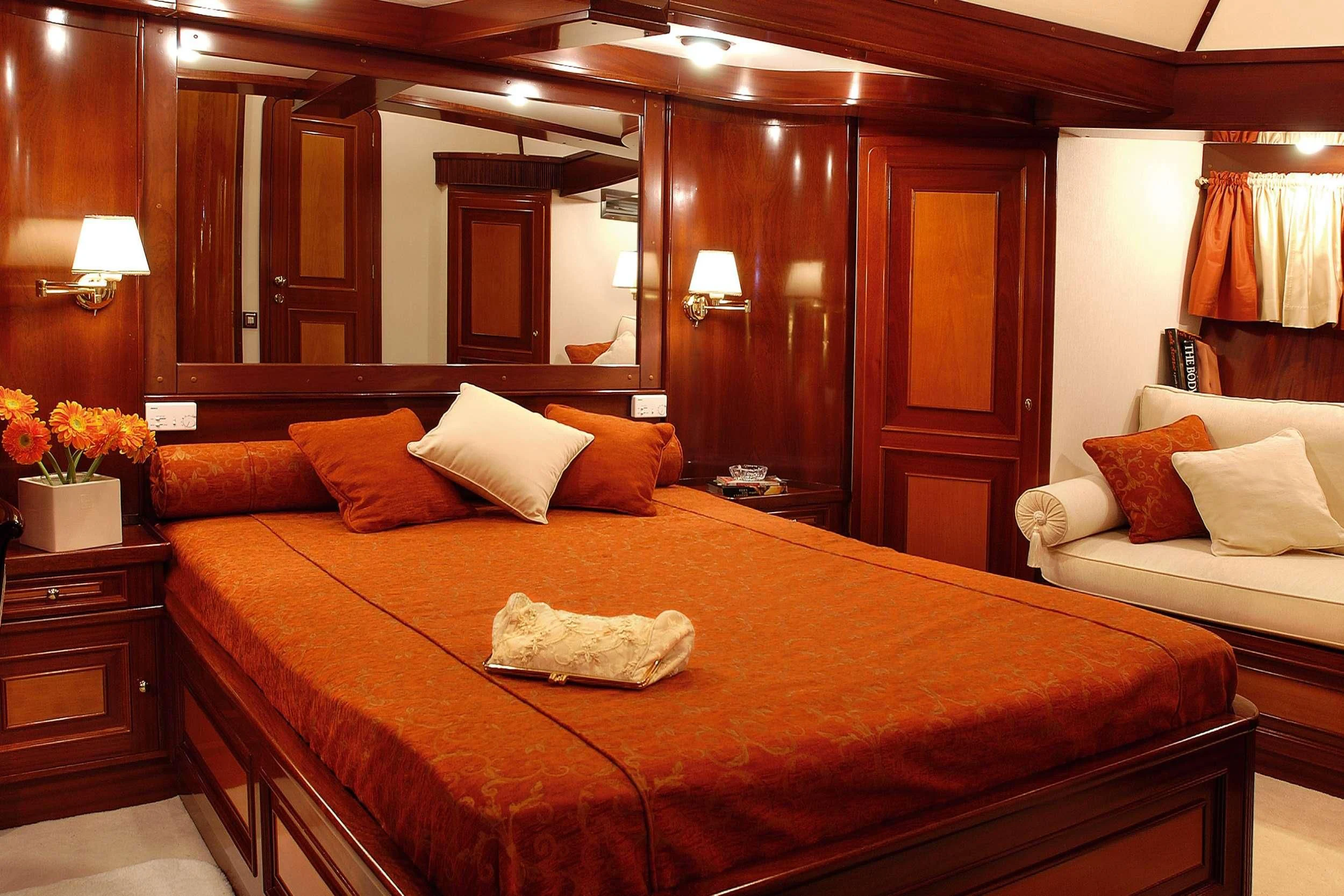 a bed with a brown comforter aboard LIANA H Yacht for Charter