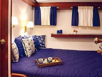 a bed with blue sheets and pillows aboard LIANA H Yacht for Charter