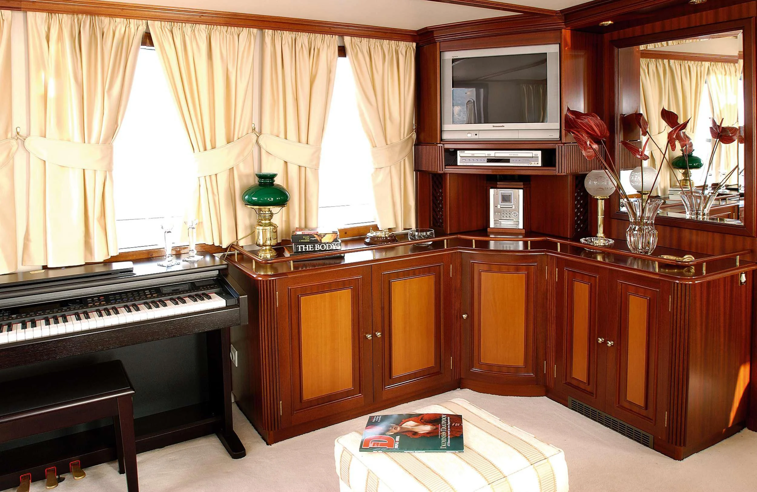 a living room with a piano and a tv aboard LIANA H Yacht for Charter