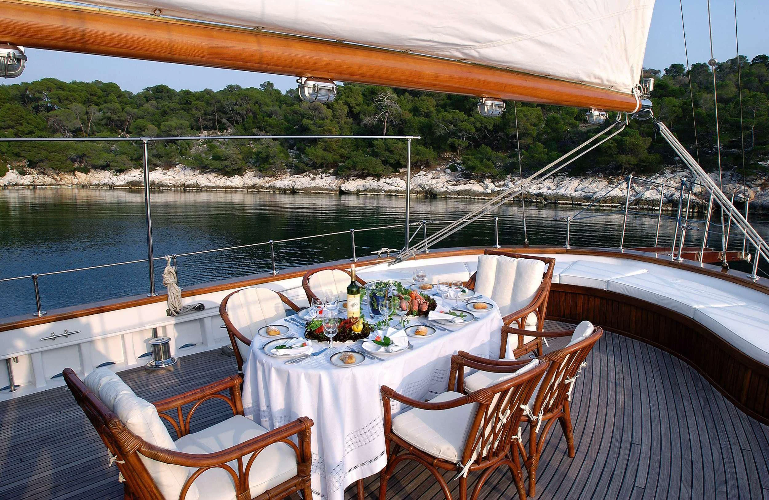 a table set for a meal on a deck overlooking a body of water aboard LIANA H Yacht for Charter