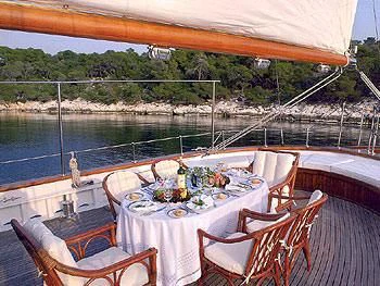a table set for a meal on a deck overlooking a lake aboard LIANA H Yacht for Charter
