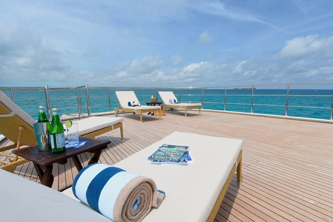 a table and chairs on a deck overlooking a beach aboard OMNIA 1 Yacht for Sale