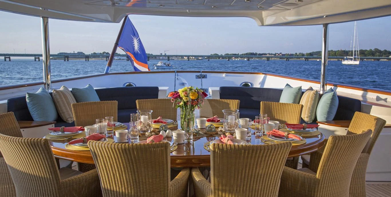 a table set for a meal on a deck overlooking a large body of water aboard OMNIA 1 Yacht for Sale
