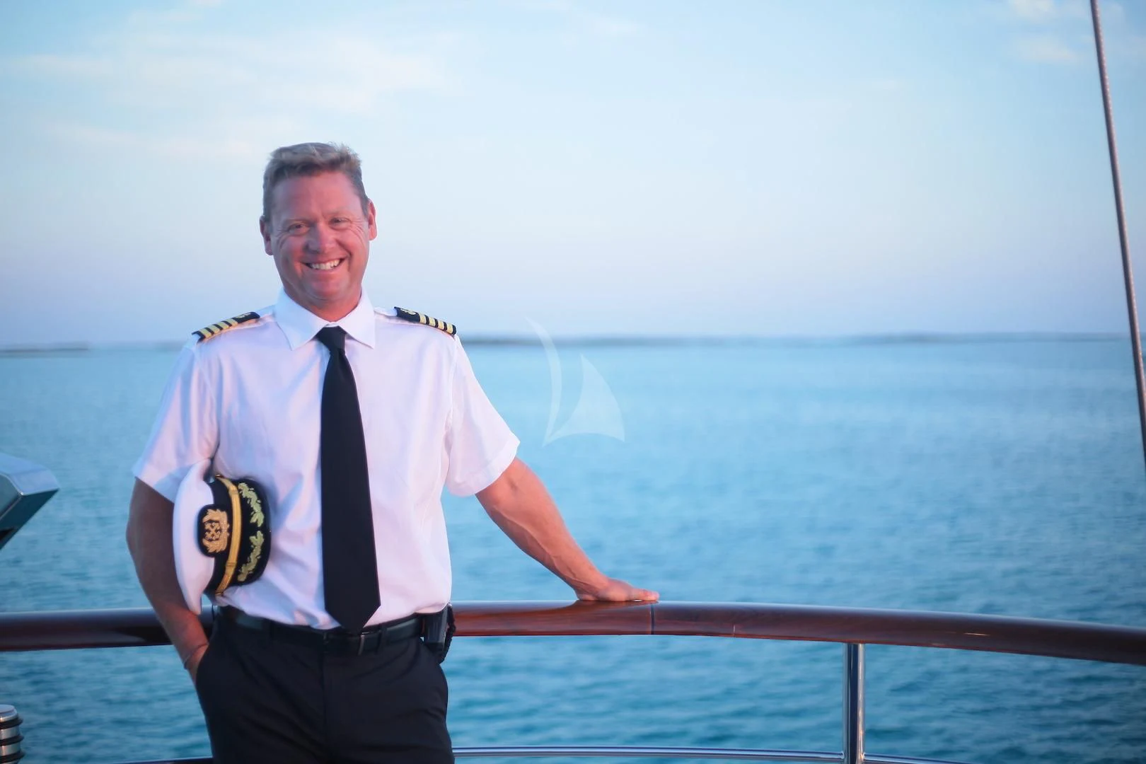 a man in a uniform standing on a railing by the water aboard OMNIA 1 Yacht for Sale