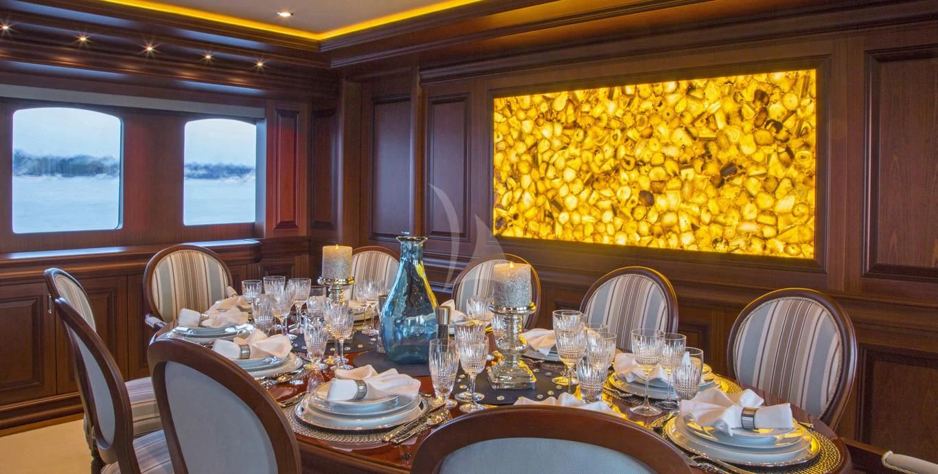 a dining room table with a large vase of yellow flowers aboard OMNIA 1 Yacht for Sale