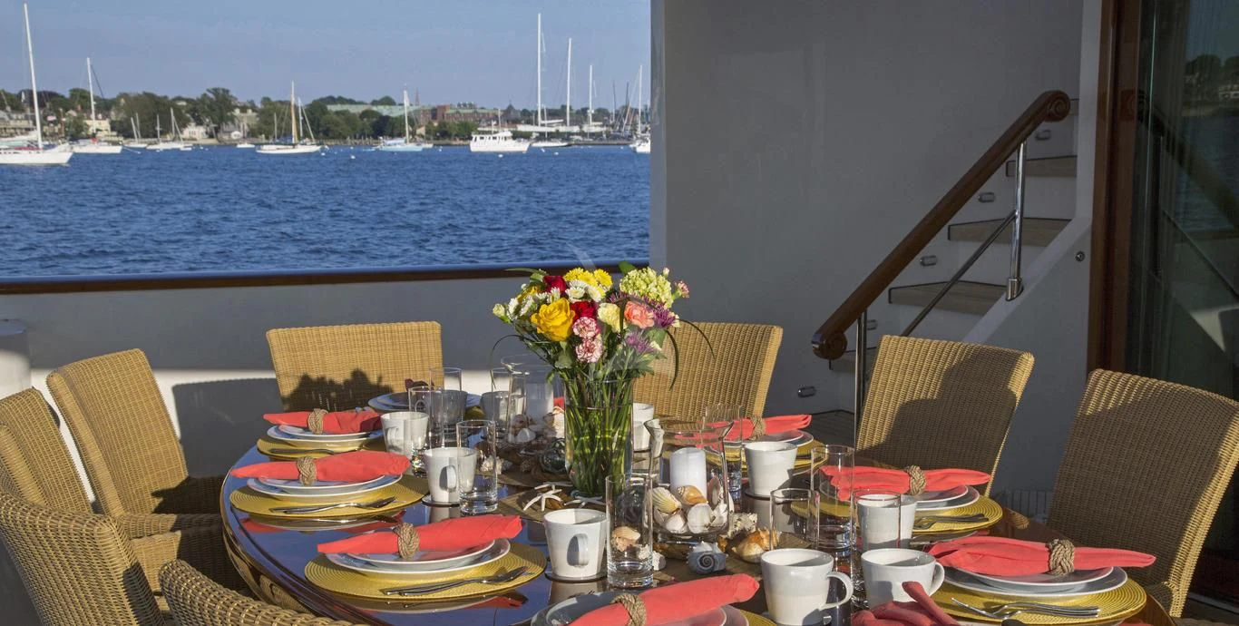a table with plates and flowers on it aboard OMNIA 1 Yacht for Sale