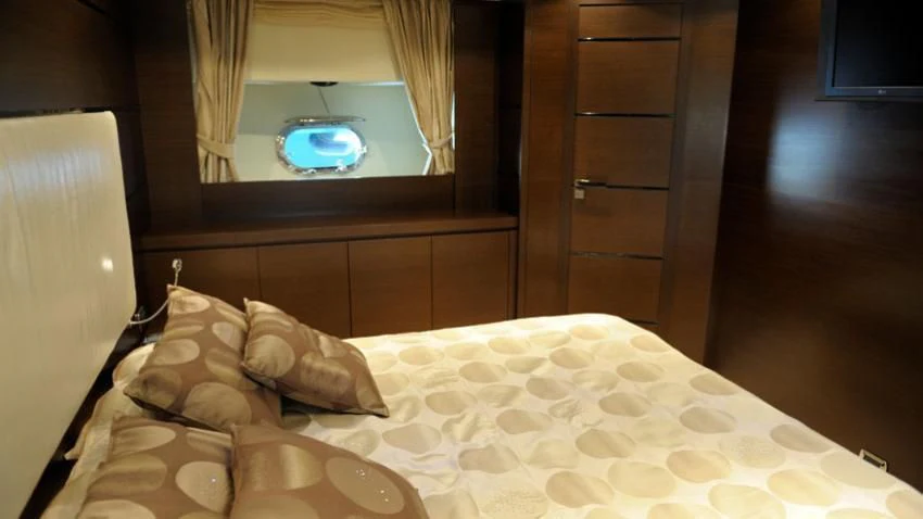 a bed with a white sheet and a round mirror on the wall aboard ANDEA Yacht for Sale