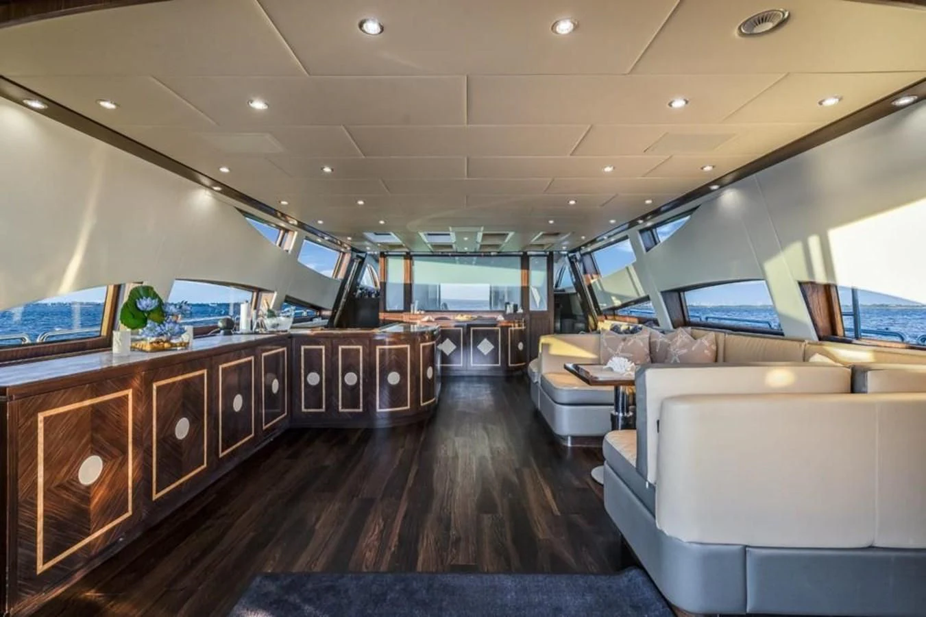 a room with a wood floor and a wood cabinet with white couches aboard ENCORE Yacht for Sale