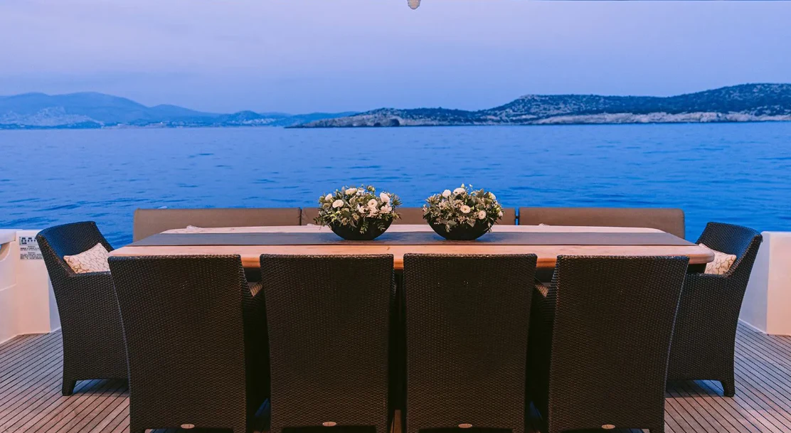 a table with chairs and a bowl of flowers on it aboard MELI Yacht for Charter