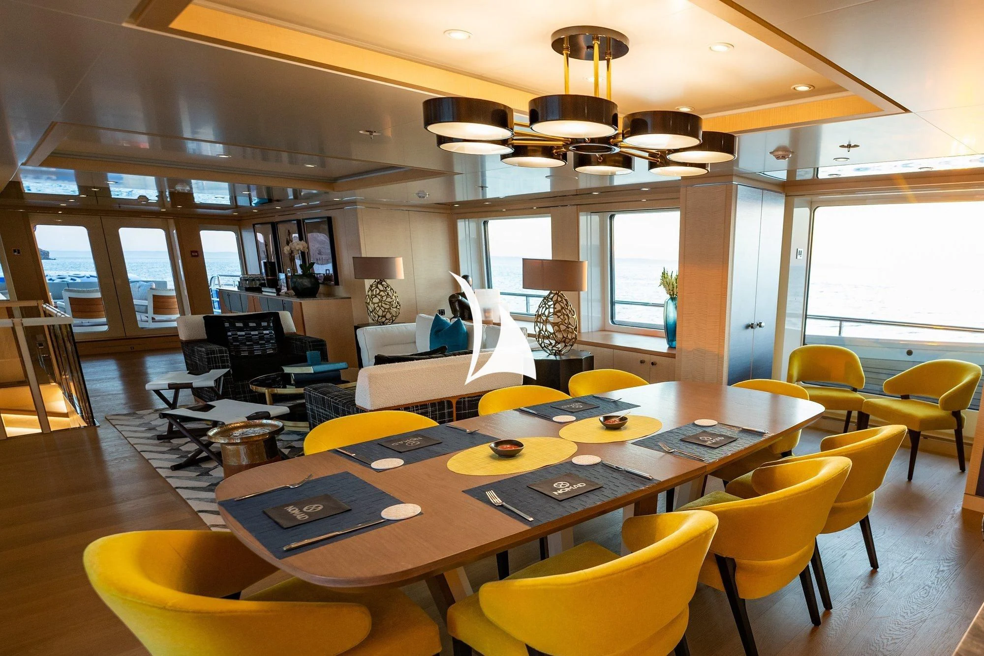 a room with yellow chairs and a table with a lamp on it aboard NOMAD Yacht for Sale