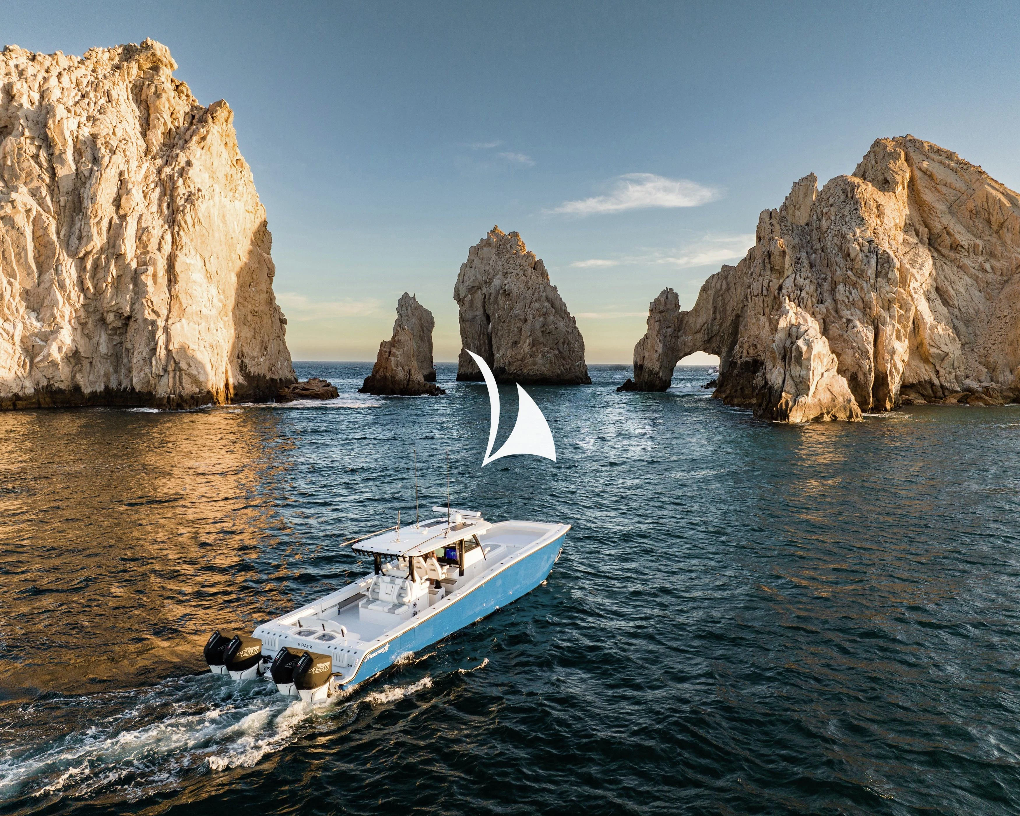 a boat on the water with Arch of Cabo San Lucas in the background aboard NOMAD Yacht for Sale