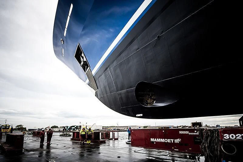 a group of people standing next to a large black object with a white object on it aboard NOMAD Yacht for Sale