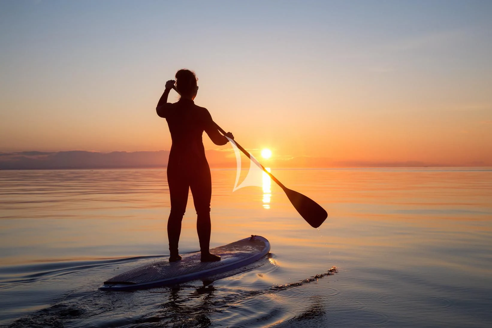 a surfer on a board with a paddle aboard XOXO Yacht for Charter