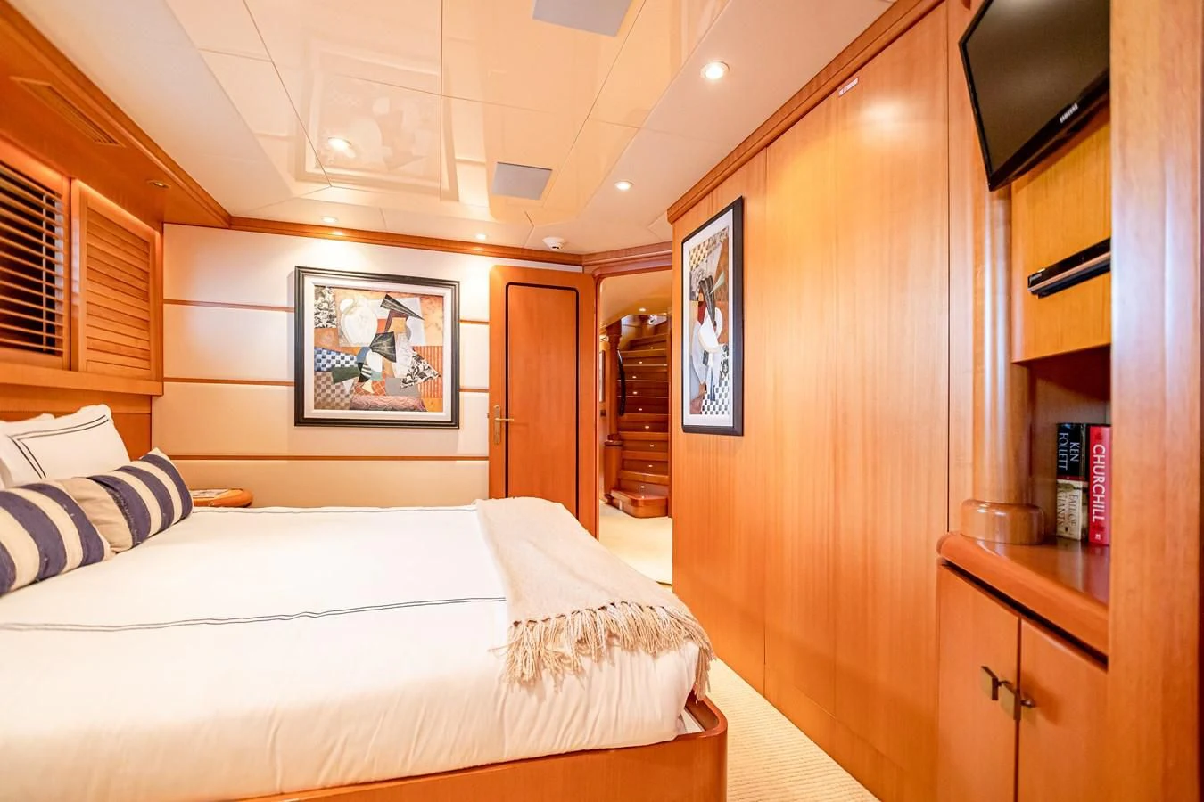 a bedroom with a bed and a wood cabinet aboard XOXO Yacht for Charter