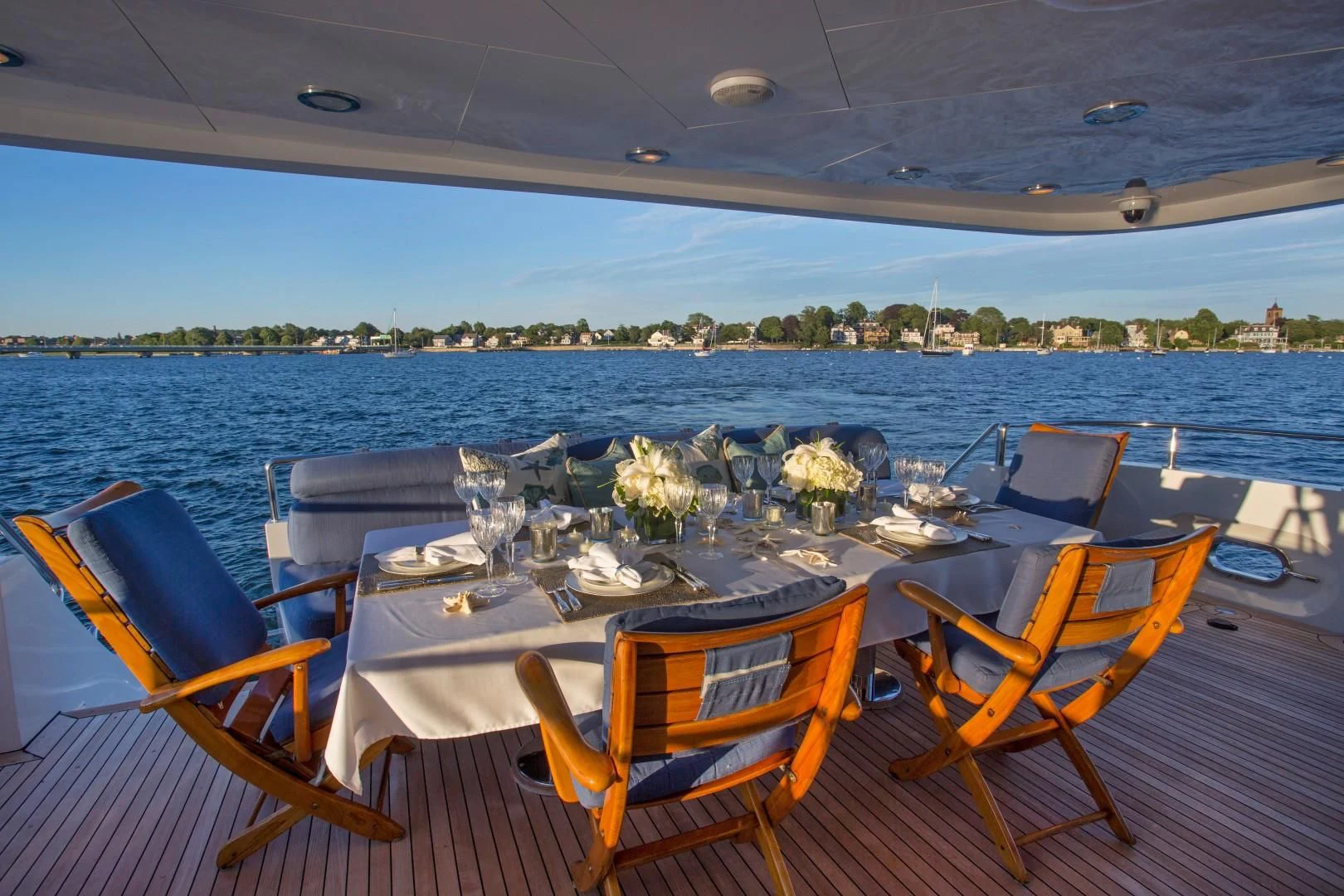 a table set for a dinner on a deck overlooking a large body of water aboard XOXO Yacht for Charter