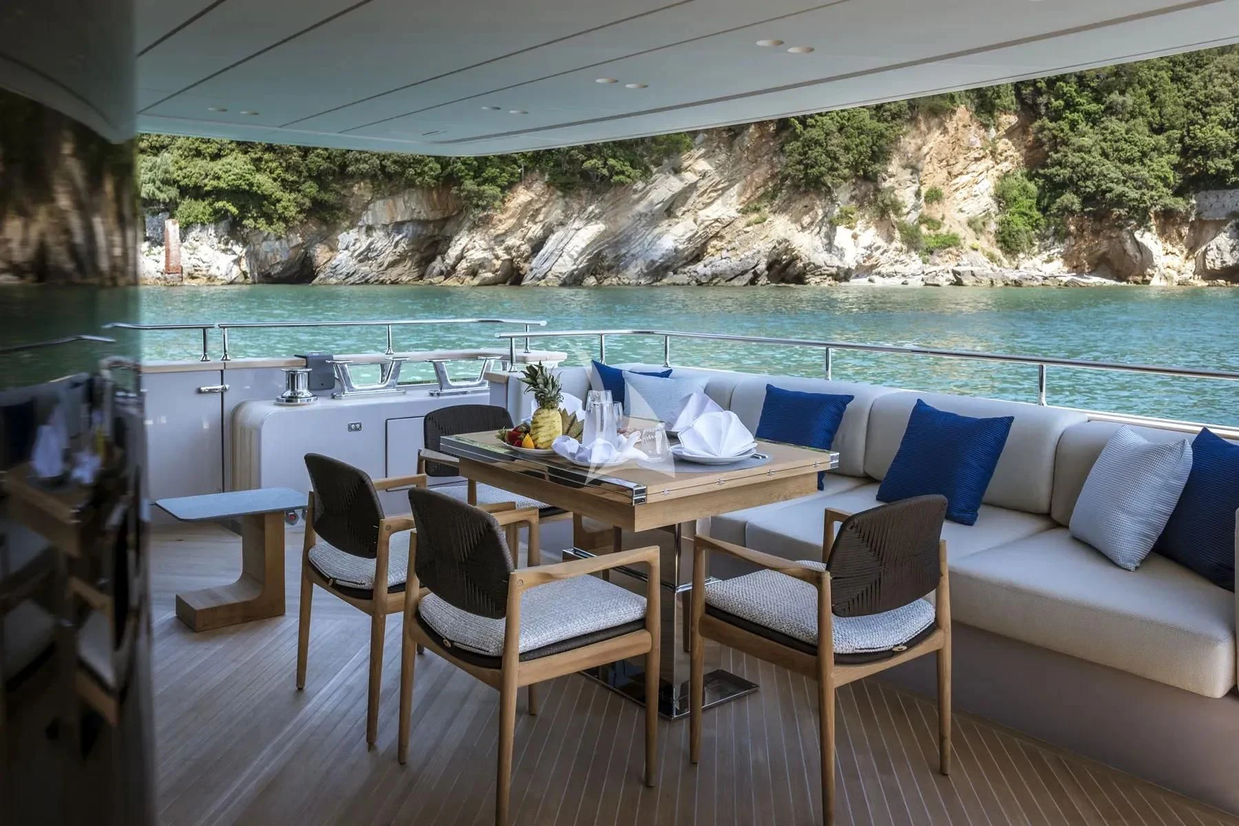 a table and chairs on a balcony overlooking a body of water aboard AKIRA Yacht for Sale