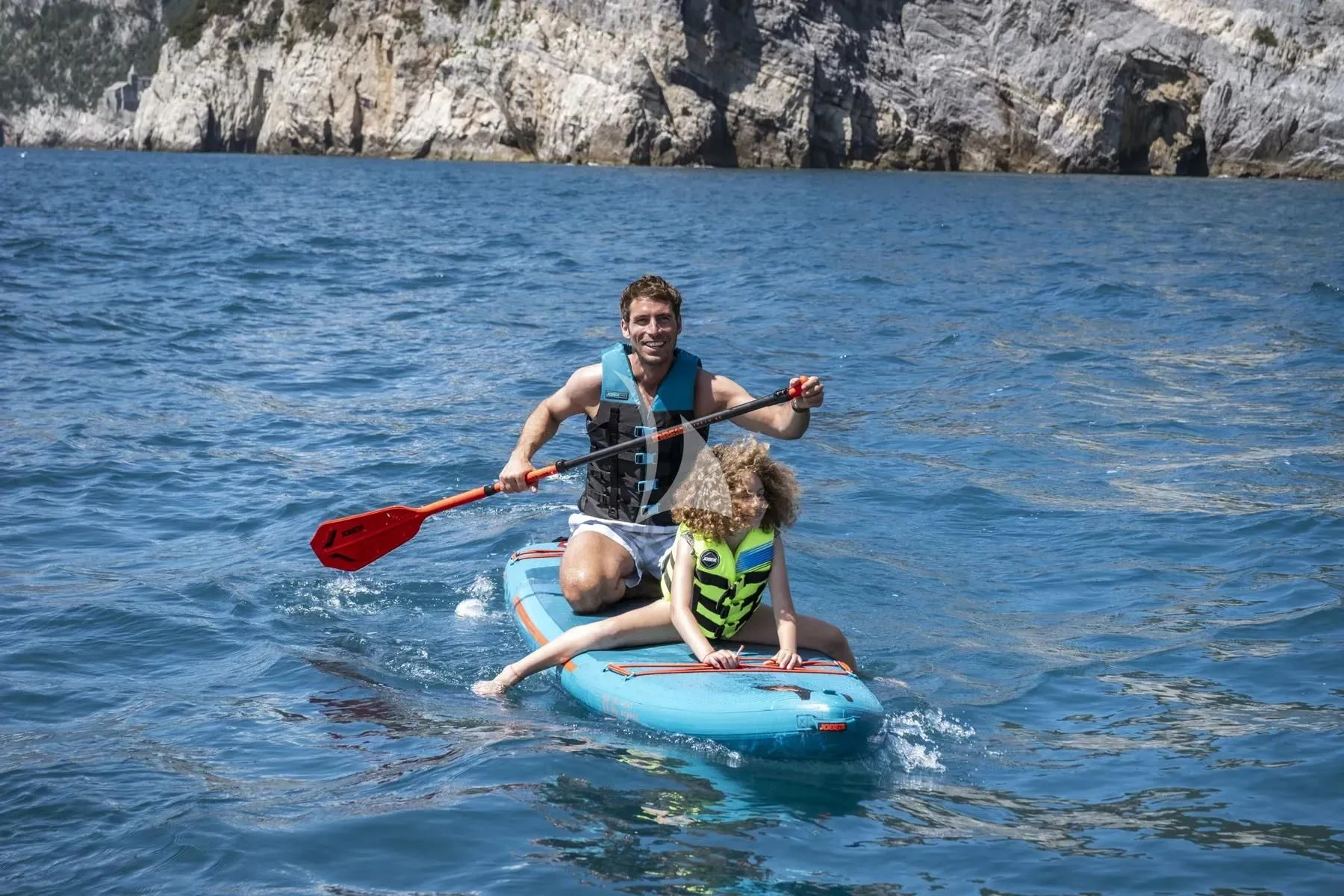 a man and a child on a paddle board in the water aboard AKIRA Yacht for Sale