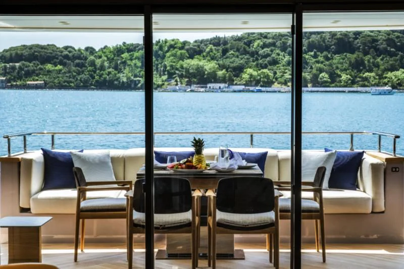 a table and chairs on a balcony overlooking a body of water aboard AKIRA Yacht for Sale